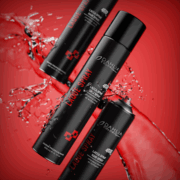 Trois bidons de 500 ml de Laque spray avec texte rouge et blanc, emballage noir, entourés d'éclaboussures d'eau sur un fond rouge vif. Dahlia Color Professionnel