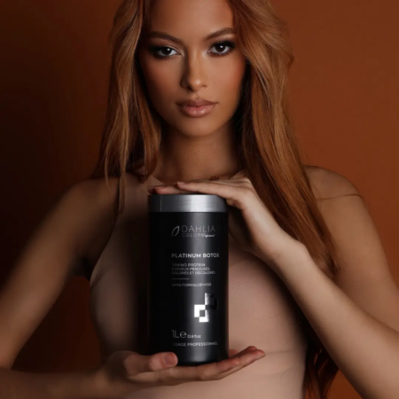 Une femme aux longs cheveux auburn tient un contenant noir « Platinum Botox » de Dahlia Color, un produit de soin capillaire professionnel mais abordable, sur un fond marron, parfait pour ceux qui recherchent la meilleure qualité au bon prix. Dahlia Color Professionnel